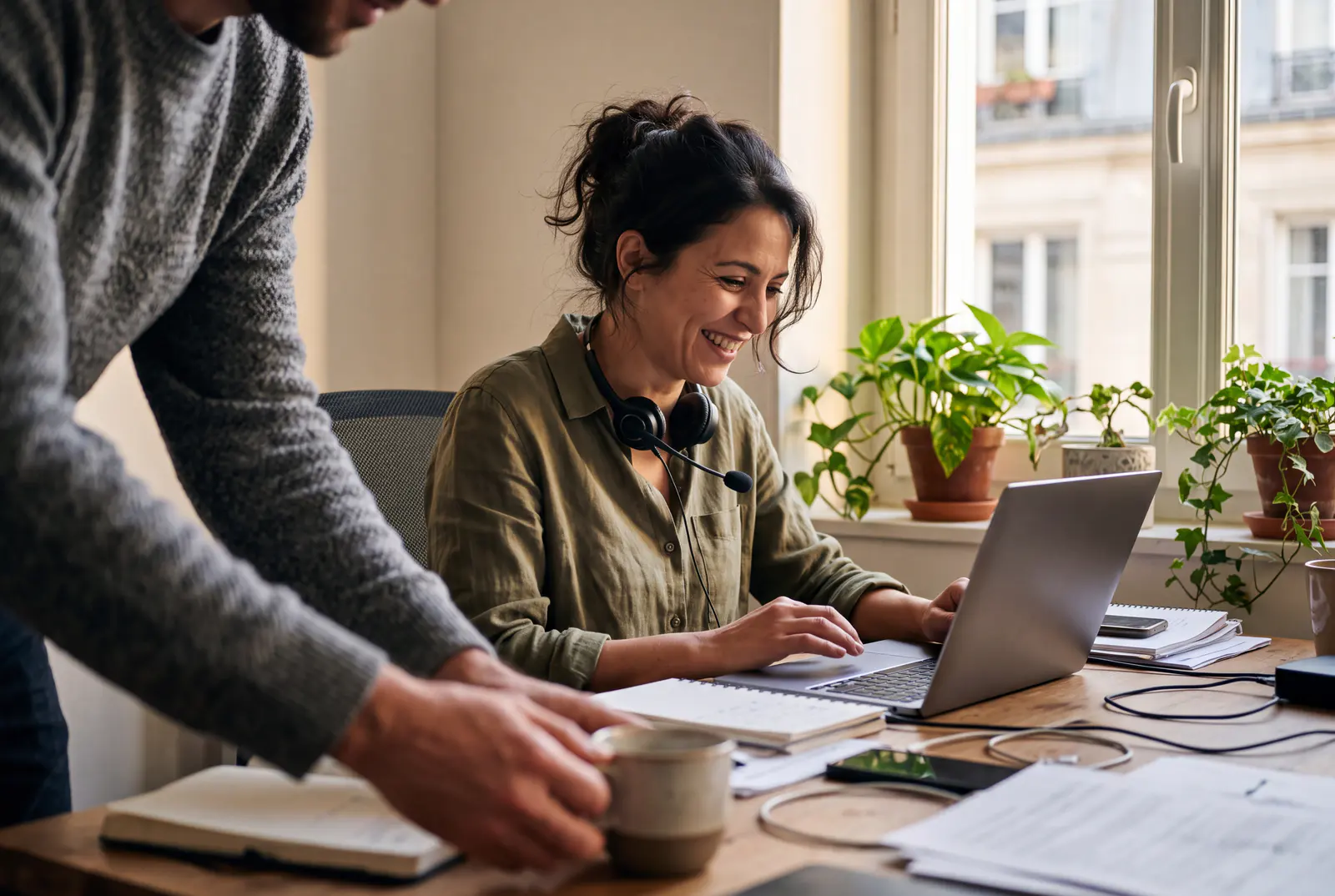 Une formatrice anime une session en ligne depuis son bureau et sourit à un participant